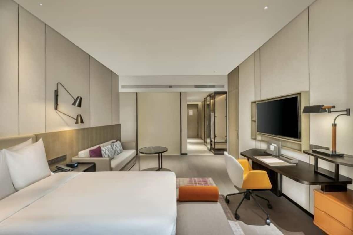 Une chambre d’hôtel moderne équipée d’un grand lit, d’un bureau, d’une chaise, d’une télévision et d’un canapé.