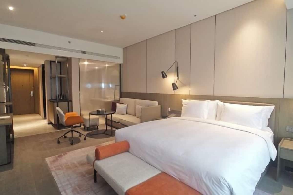 Une chambre d’hôtel avec un grand lit, un bureau, une chaise et un téléviseur.