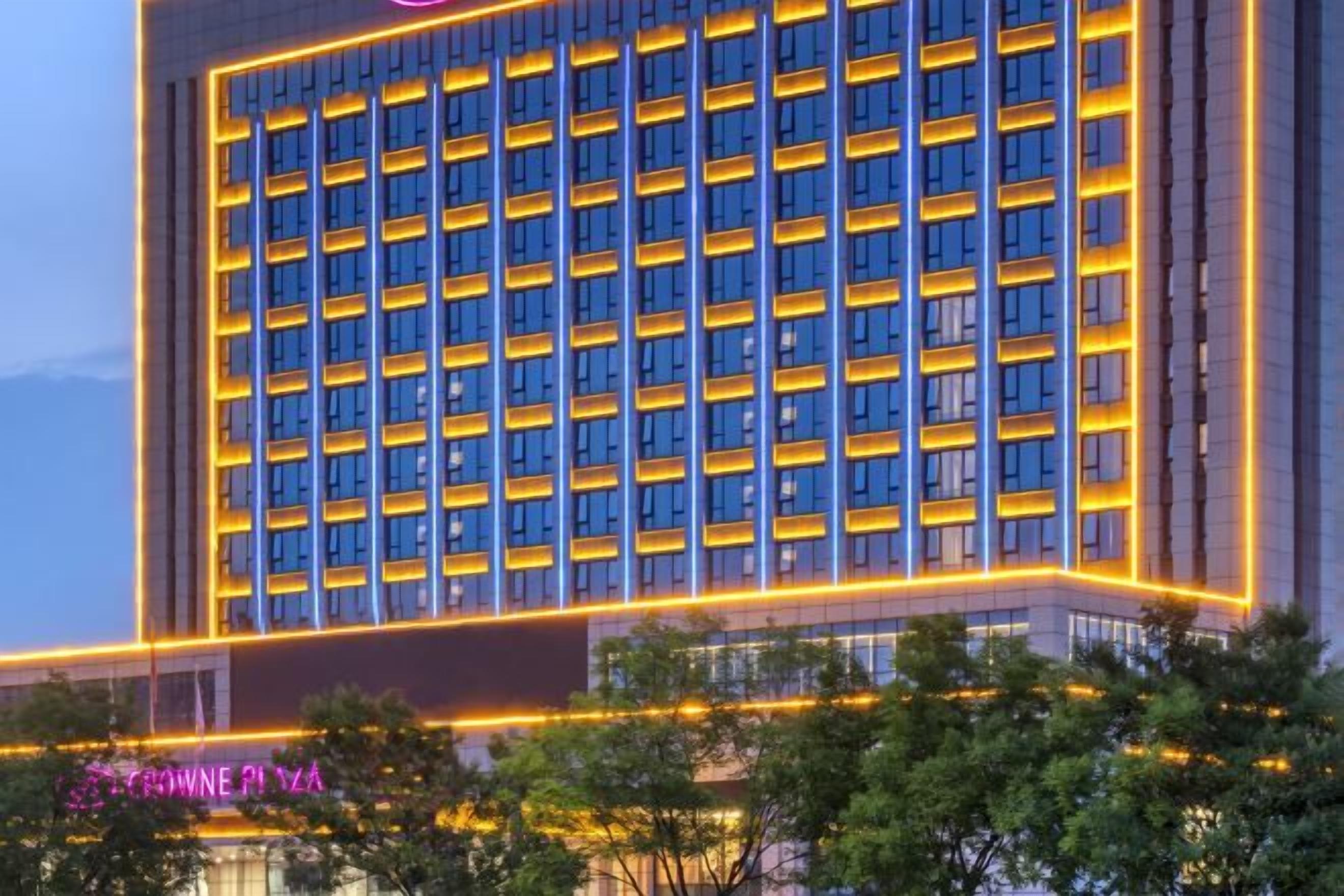 A multi-story building with a grid of windows, illuminated by yellow lights along the edges.