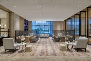 A spacious lobby with seating areas, a patterned carpet, and large windows offering a view of the cityscape. - Crowne Plaza LANZHOU NEW AREA by IHG (Gaolan)