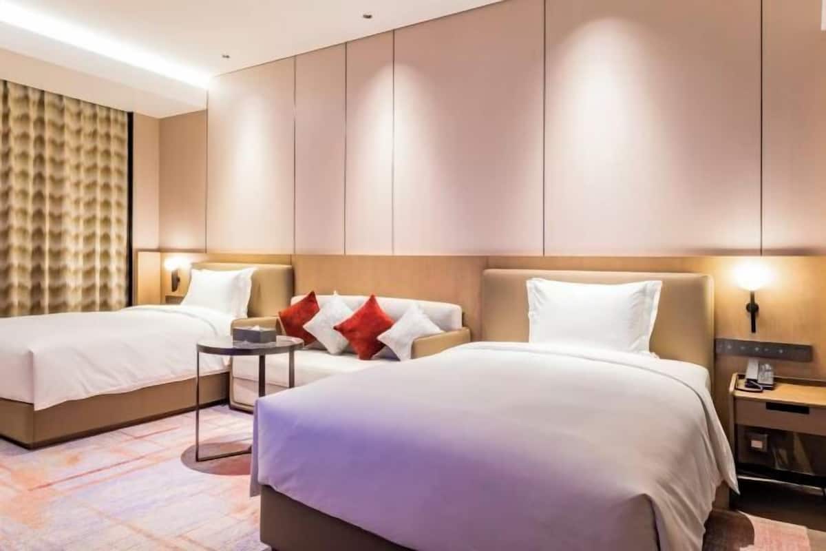 Une chambre d’hôtel avec deux lits, un canapé, une petite table et une table de chevet.