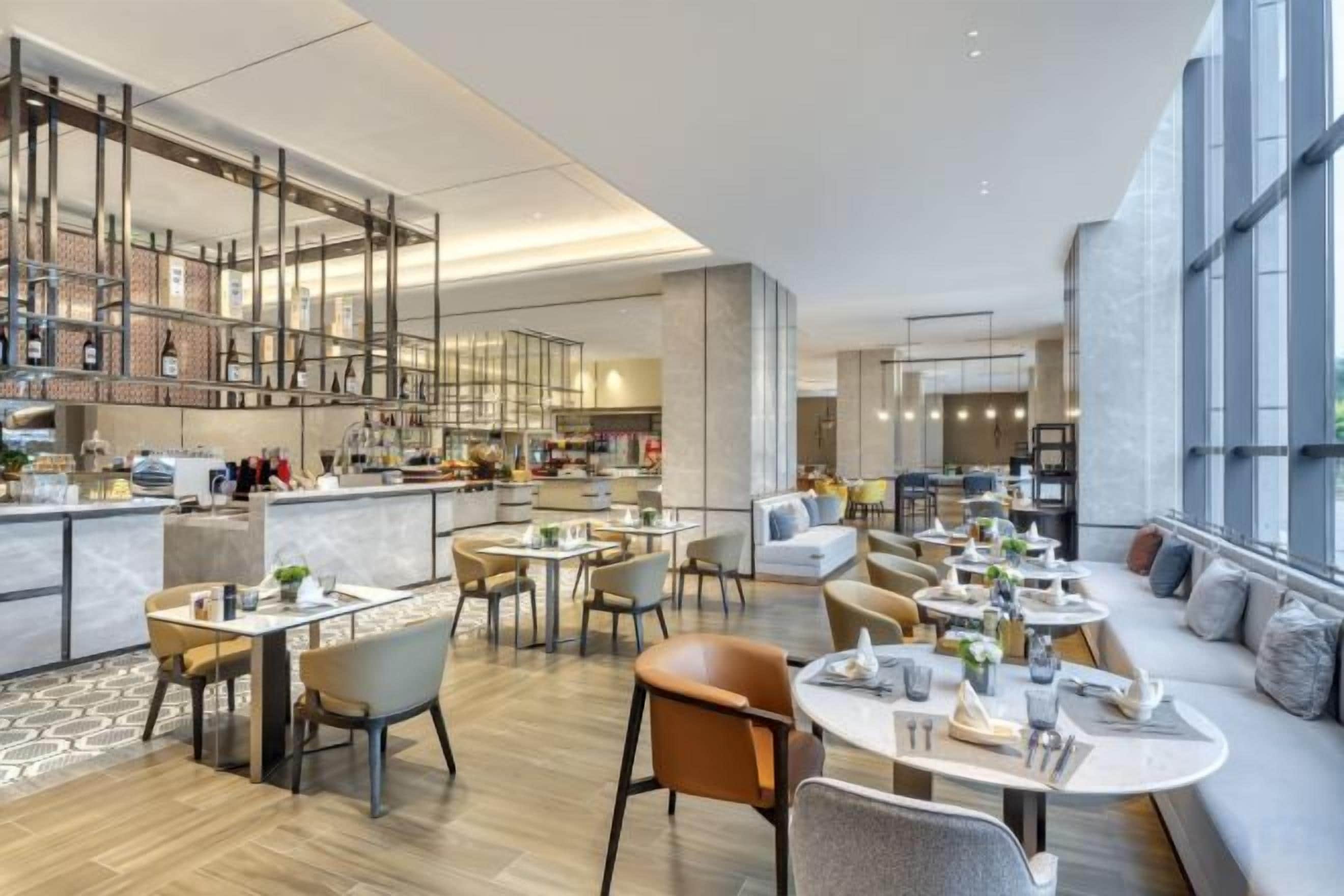 A modern hotel lobby with a bar area, seating arrangements, and large windows.