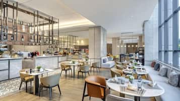 A modern hotel lobby with a bar area, seating arrangements, and large windows.