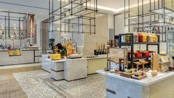 A modern hotel lobby with a marble reception desk, a glass display case, and a patterned rug.