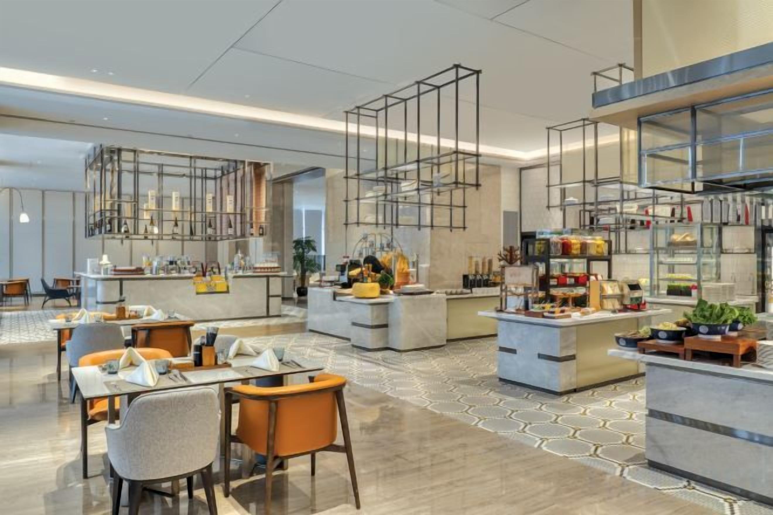 A modern hotel lobby with a central bar area, seating arrangements, and a patterned floor.