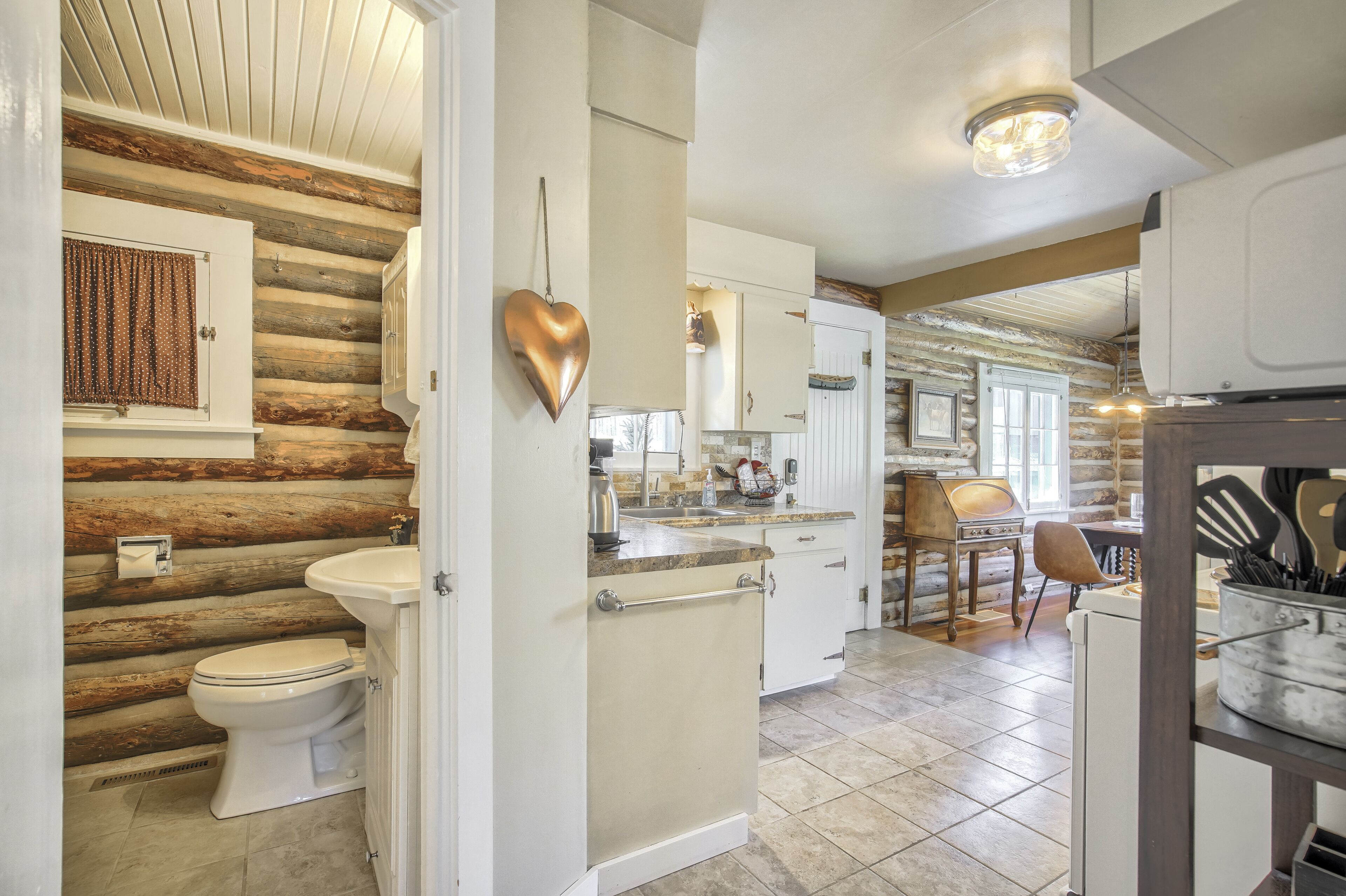A log cabin interior with a bathroom, kitchen, and dining area.