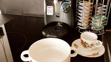 A kitchen with a Bosch coffee maker, a TASSIMO coffee pot, a mug with a cartoon character, and a stack of disposable cups.