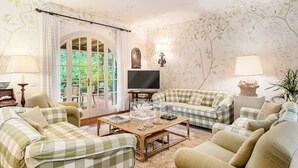 Uma sala de estar acolhedora com sofás xadrez, uma mesa de centro de madeira e uma televisão.