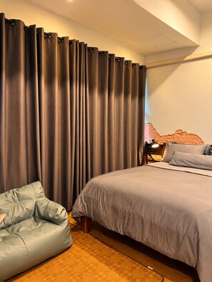 A bedroom with a bed, a seating area, and a wall with a textured pattern. - CHERN CHIANGMAI BOUTIQUE (Chiang Mai)