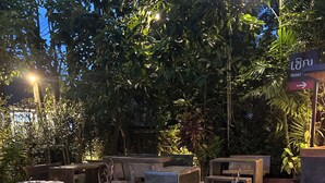 An outdoor seating area with tables and chairs, surrounded by lush greenery and trees. - CHERN CHIANGMAI BOUTIQUE (Chiang Mai)