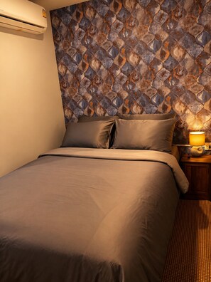 A hotel room with a bed, a nightstand with a lamp, and a wall with a patterned design. - CHERN CHIANGMAI BOUTIQUE (Chiang Mai)