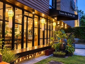 An exterior view of a restaurant with a wooden facade, large windows, and hanging lanterns. - CHERN CHIANGMAI BOUTIQUE (Chiang Mai)