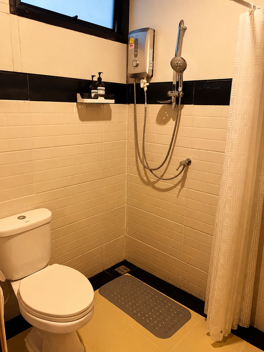 Un baño pequeño con inodoro, ducha y un perchero para toallas.
