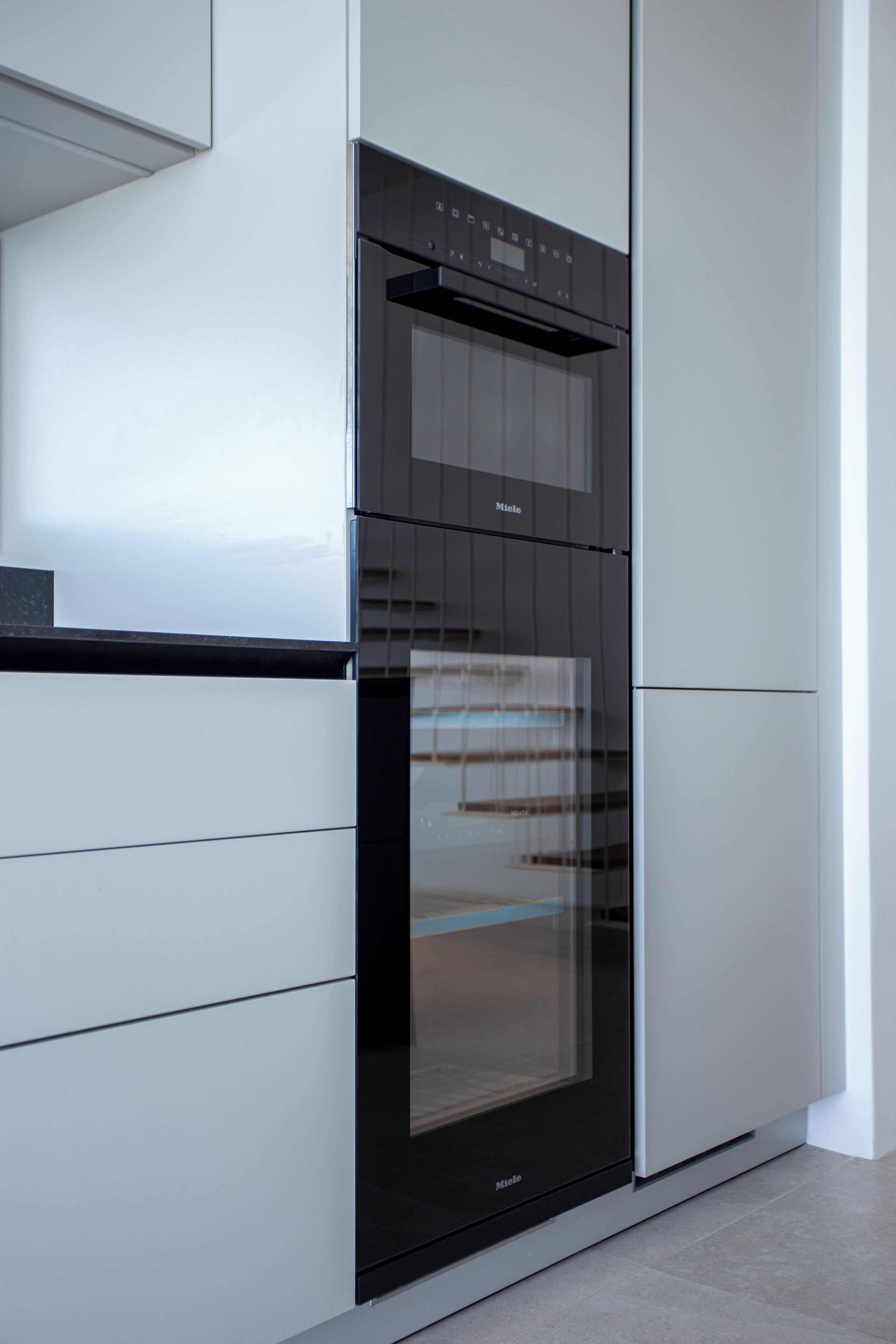 A modern kitchen with a built-in oven and microwave, white cabinetry, and a sleek design.