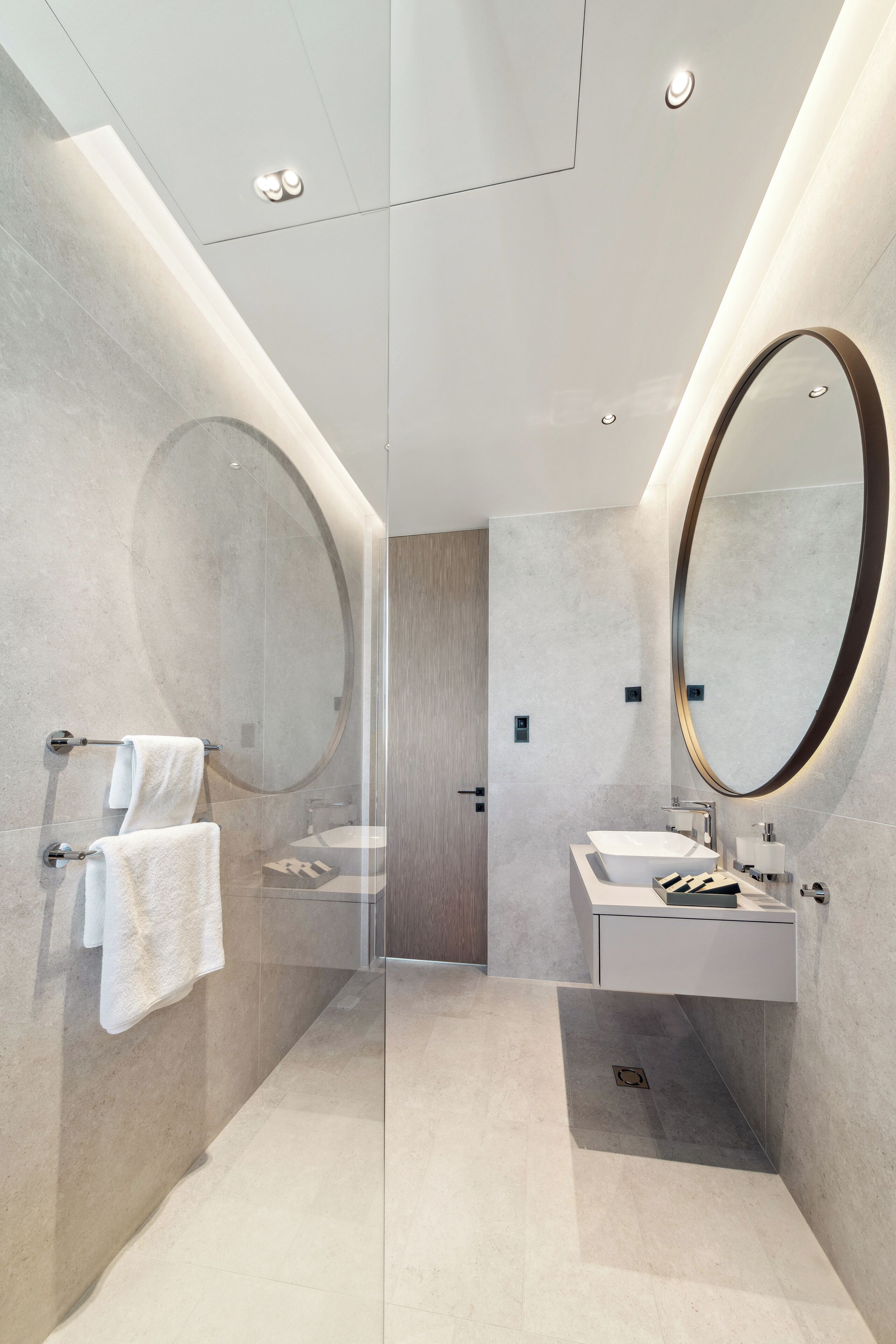 A modern bathroom with a glass shower enclosure, a large mirror, and a white sink.