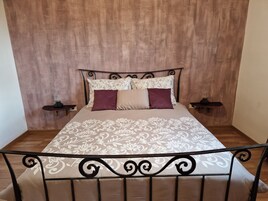 Una cama bien tendida con ropa de cama estampada, cabecera y dos mesitas de noche con lámparas.