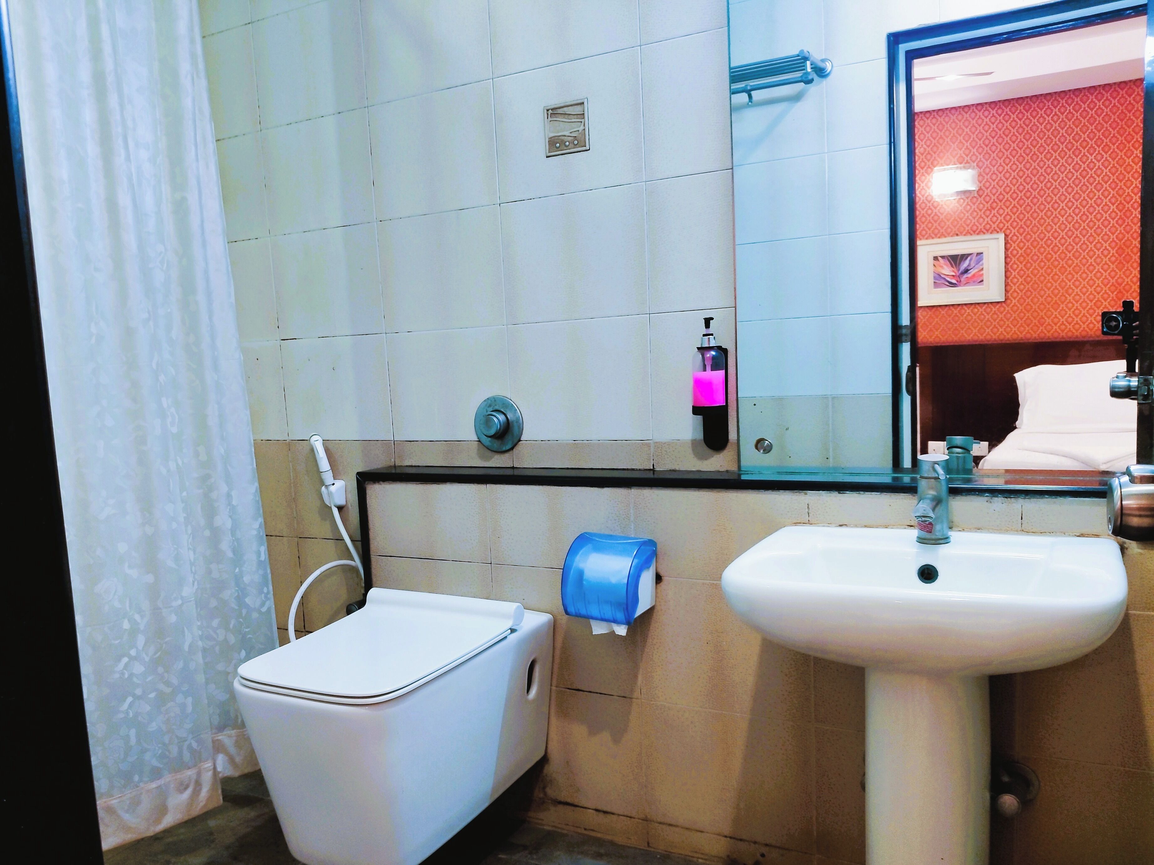 A bathroom with a toilet, a sink, a mirror, and a shower area.