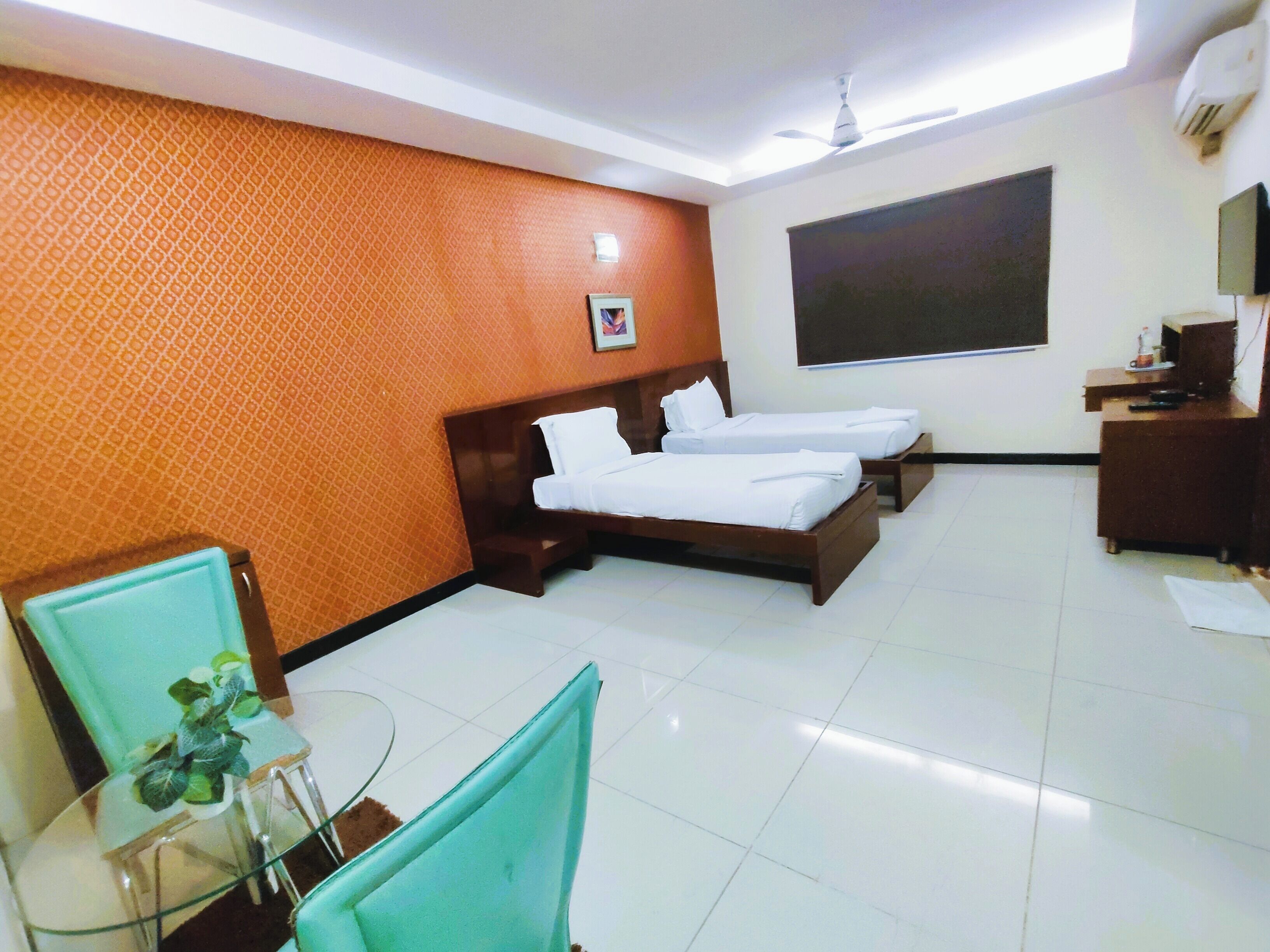 A hotel room with two beds, a desk, a chair, and a TV.