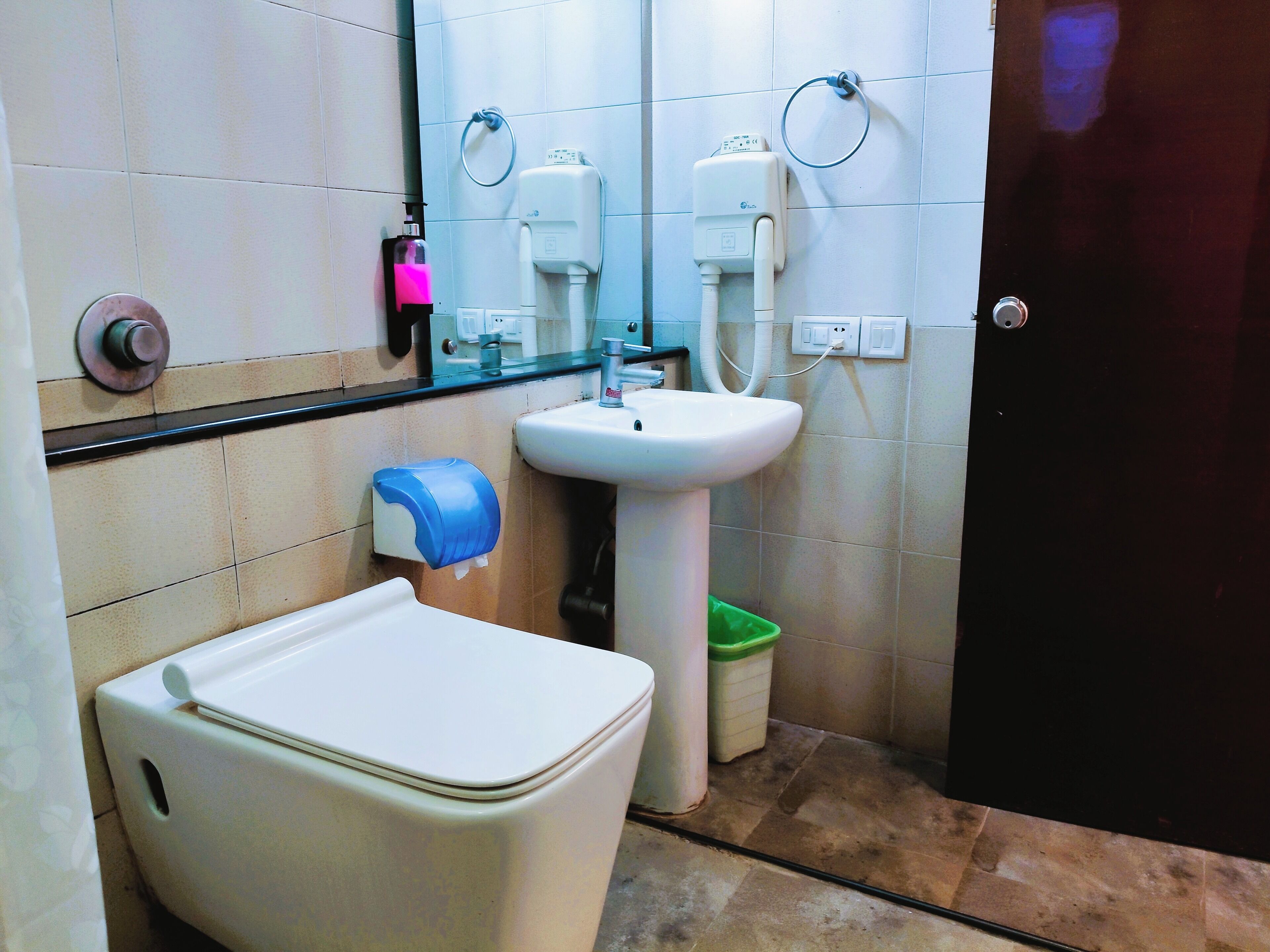 A bathroom with a toilet, sink, and hand dryer.