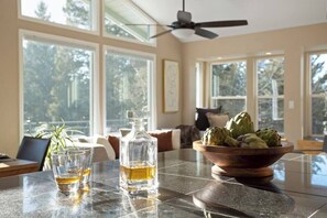 A dining area with a table, two glasses of a clear liquid, a bottle, and a bowl of green vegetables.