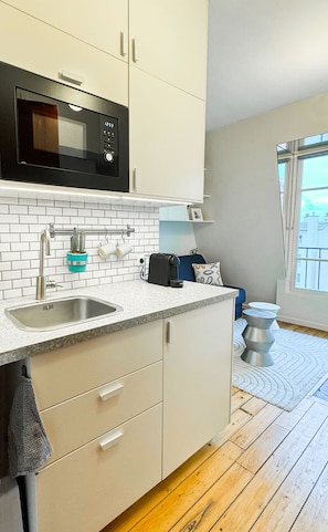 Enjoy a city view from the kitchen, featuring a microwave, sink, and tiled backsplash.