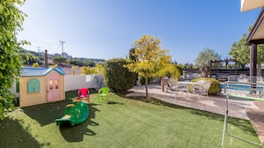 A backyard with a play area, a small shed, and a pool. - Villa Artemis (Paralimni)