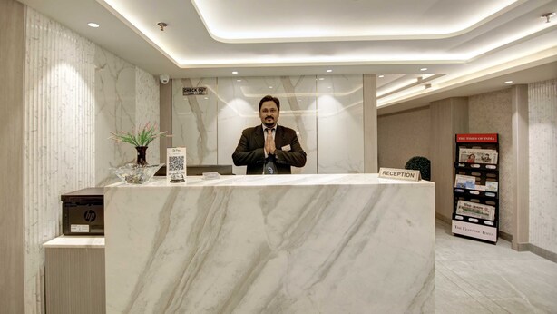 A reception desk with a marble top, a sign indicating 'Check Out', a QR code, and a 'Reception' sign. - East Park Inn (New Delhi)
