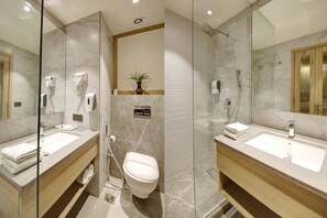 A modern bathroom with a marble sink, a toilet, and a shower area.