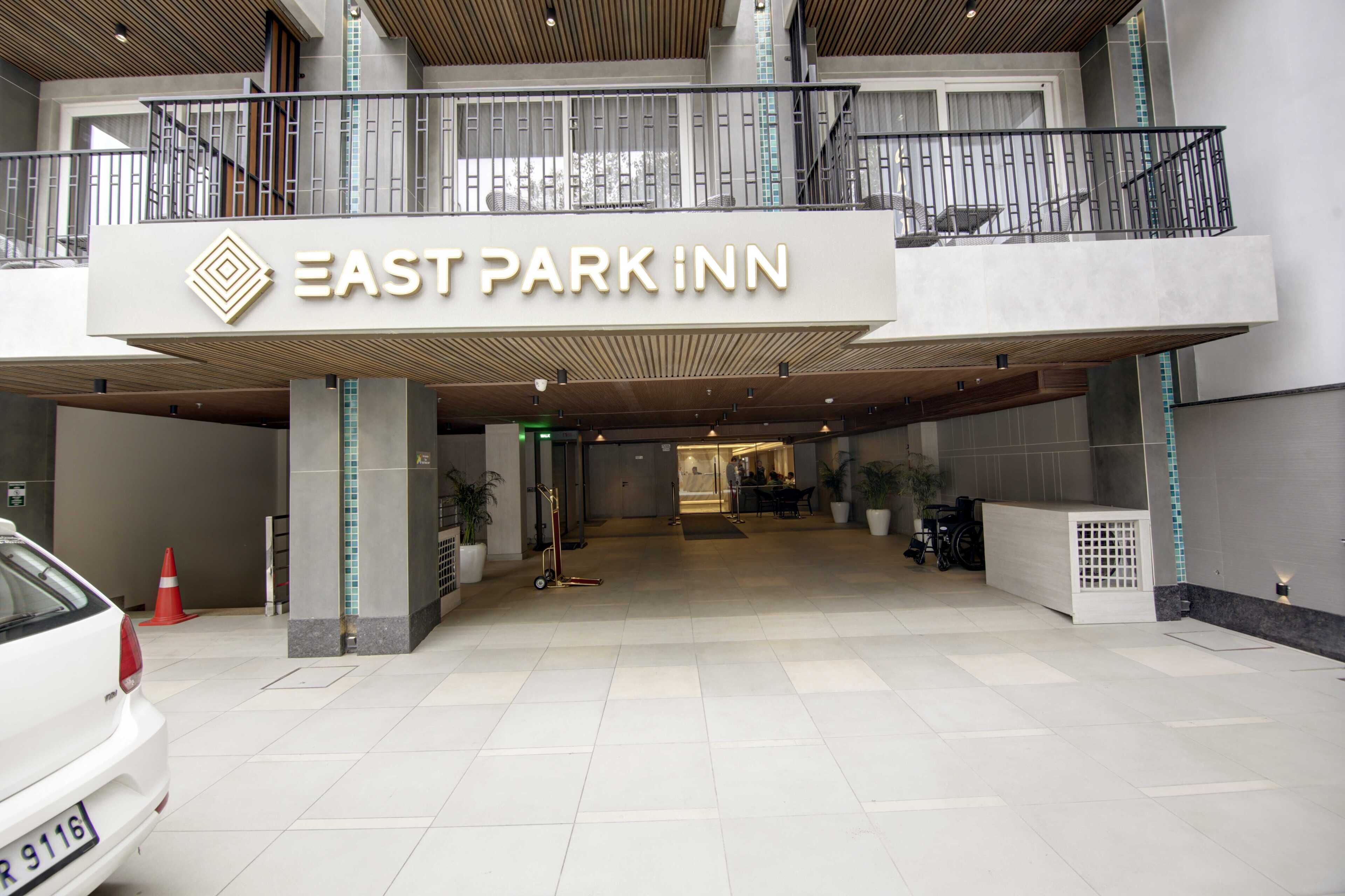 La entrada al East Park Inn, con un letrero llamativo, un corredor cubierto y un mostrador de recepción.