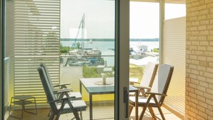 Un balcon avec deux chaises et une table, donnant sur une marina où sont amarrés des bateaux.