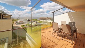 Un balcon donnant sur une marina, un coin repas avec des chaises et une balustrade en verre.