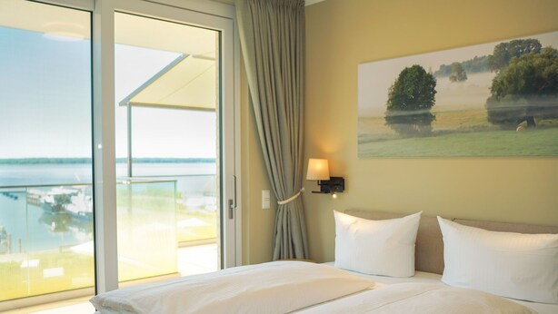 Une chambre d’hôtel avec un grand lit, une vue sur la mer et un tableau accroché au mur.
