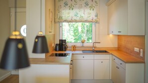 Une cuisine moderne avec un plan de travail en bois, un évier encastré et des luminaires suspendus.