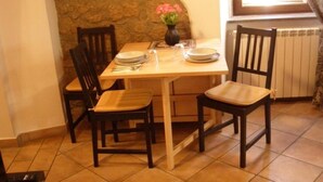 A dining area with a stone wall, a table set with plates, a vase with flowers, and two chairs. - Parva Domus in 29 (Morlupo)