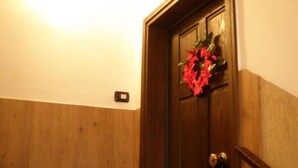 A wooden door with a red wreath, a light switch, and a wooden handrail. - Parva Domus in 29 (Morlupo)