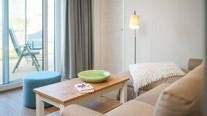 A modern living room with a sofa, a small wooden table, a green bowl, and a lamp. - Bright Top-Floor Suite with Large Rooftop Terrace and Harbor View (Rankwitz)