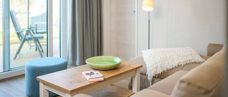 En moderne stue med en sofa, et lille træbord, en grøn skål og en lampe.
