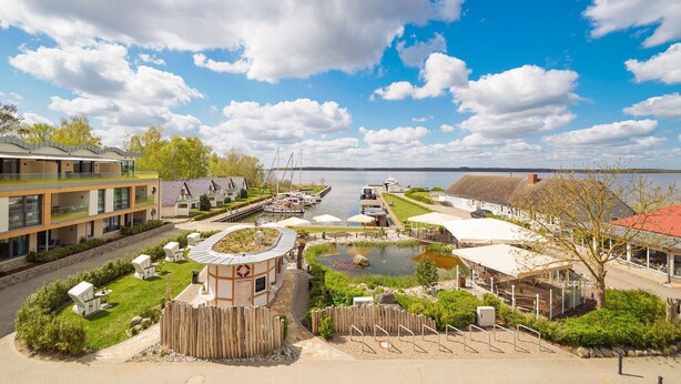 A lakeside hotel with a central courtyard, outdoor seating, and a view of the lake. - Spacious Top-Floor Suite with Large Rooftop Terrace – Ideal for Families (Rankwitz)