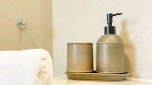A bathroom with a white towel, a beige soap dispenser, and a matching container on a white countertop. - Spacious Top-Floor Suite with Large Rooftop Terrace – Ideal for Families (Rankwitz)