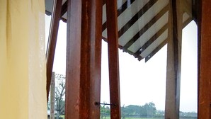 Una mesa con un hervidor, botellas y una bandeja de bocadillos junto a una ventana que da a un campo verde.