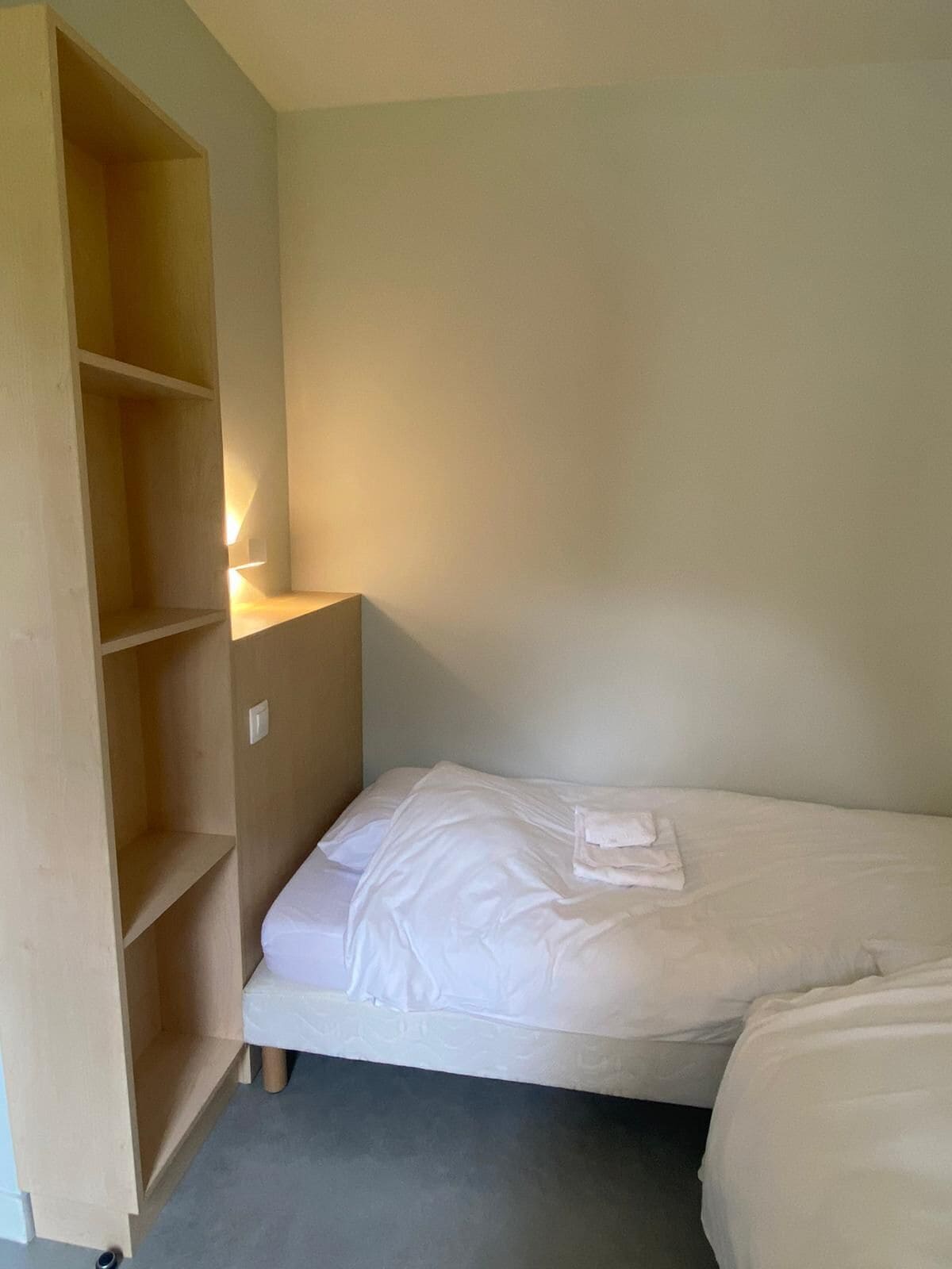 Une petite chambre avec un lit simple, une armoire en bois et une table de chevet.