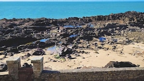 Ein felsiger Strand mit einer Steinmauer und einem Holztor.