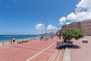 A coastal promenade with a brick walkway, street lamps, and a row of buildings.