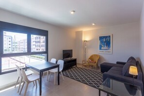 A modern living room with a dining area, a flat-screen TV, a sofa, and a chair.