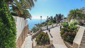 Une promenade en bord de mer, agrémentée d’escaliers en pierre, d’une végétation luxuriante et offrant une vue sur la mer.
