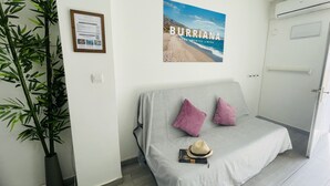 Une chambre à coucher avec un lit, une affiche représentant une plage, une plante en pot et une porte.