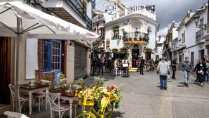 Une rue avec un café, des tables en terrasse et un vélo jaune décoré de fleurs.
