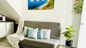 Un salon moderne avec un canapé gris, une petite table d’appoint et une plante en pot.