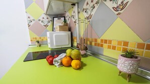 Une cuisine avec un plan de travail vert, un micro-ondes blanc et une plante en pot.