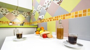 Un comptoir de cuisine avec un panier de fruits, une bouteille et deux verres de café.